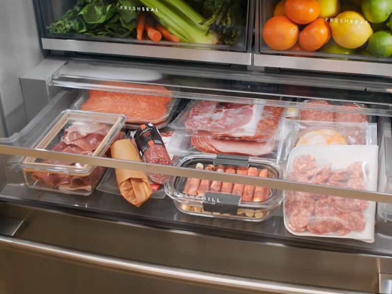 An open deli drawer with various meats