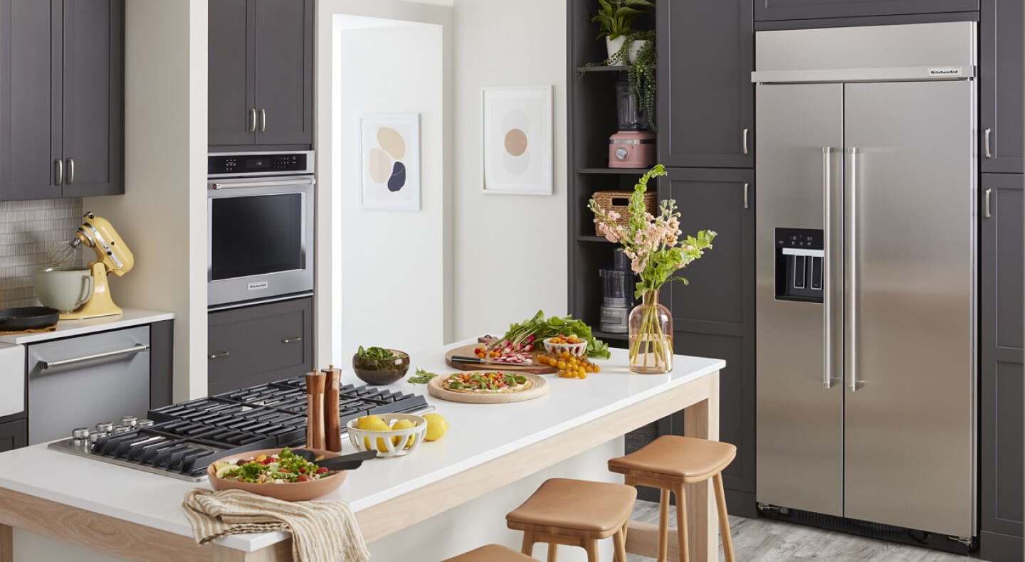 A kitchen with an island and a stainless steel side-by-side refrigerator