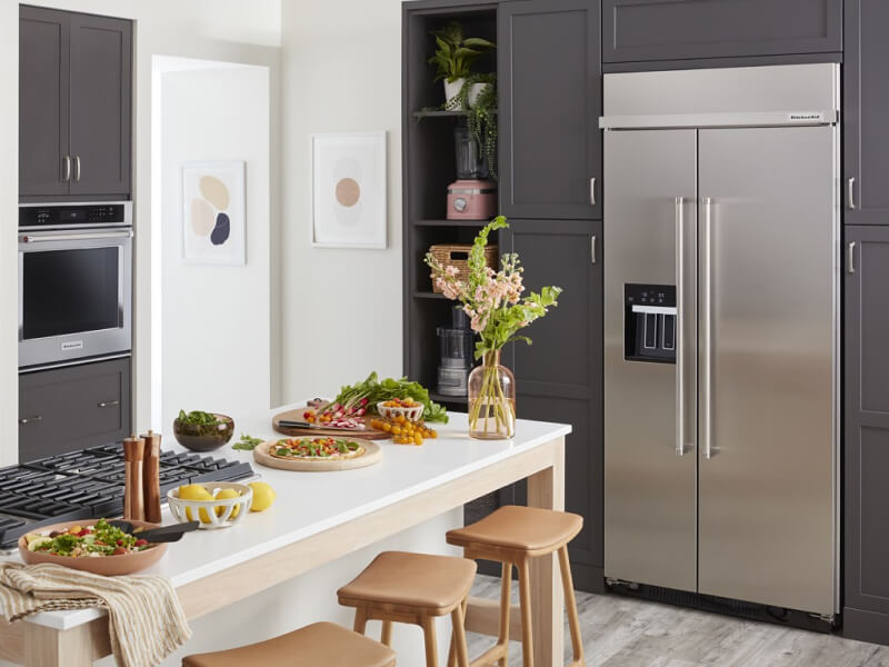 A kitchen with an island and a stainless steel side-by-side refrigerator