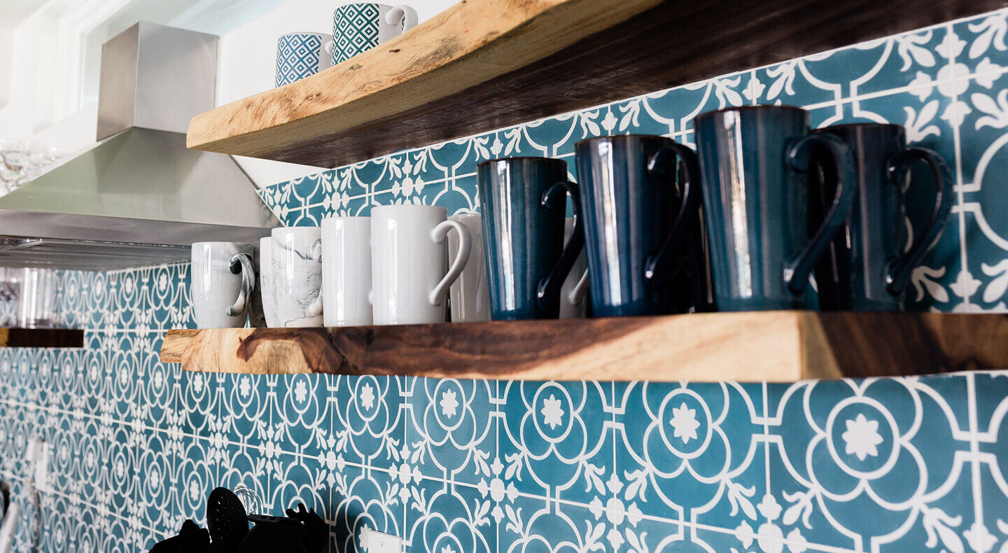 Mugs on floating wood shelves installed on a patterned wall