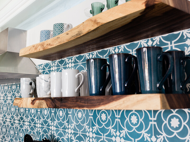 Mugs on floating wood shelves installed on a patterned wall