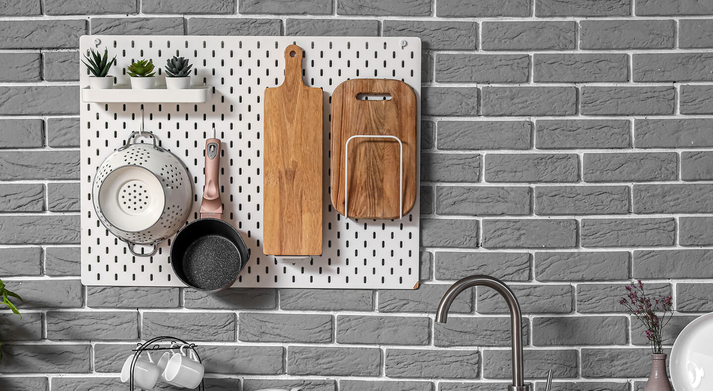Wood block cutting boards, a pot and a colander hanging on a peg board