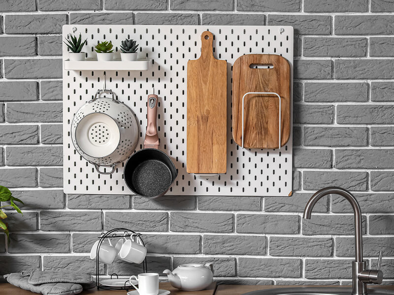 Wood block cutting boards, a pot and a colander hanging on a peg board