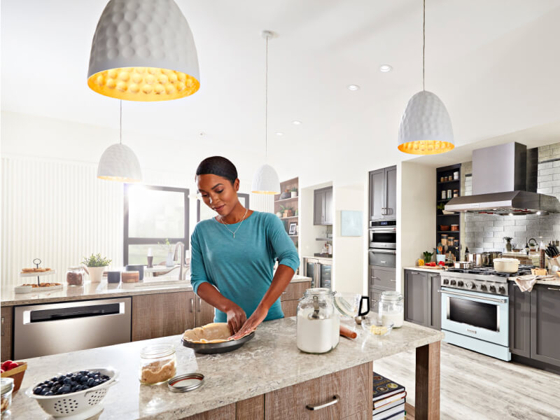 Person making a blueberry pie in their open kitchen