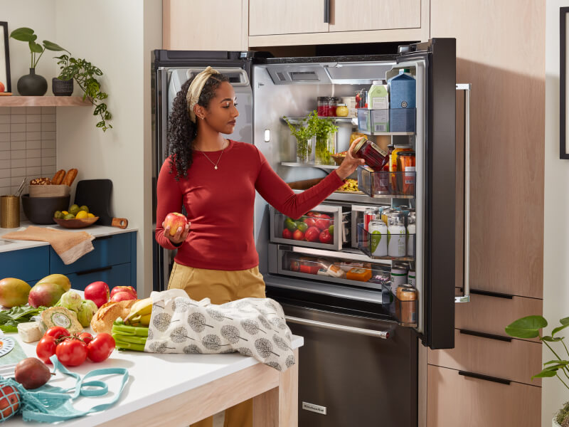 Person loading fresh groceries into a KitchenAid®  French door refrigerator