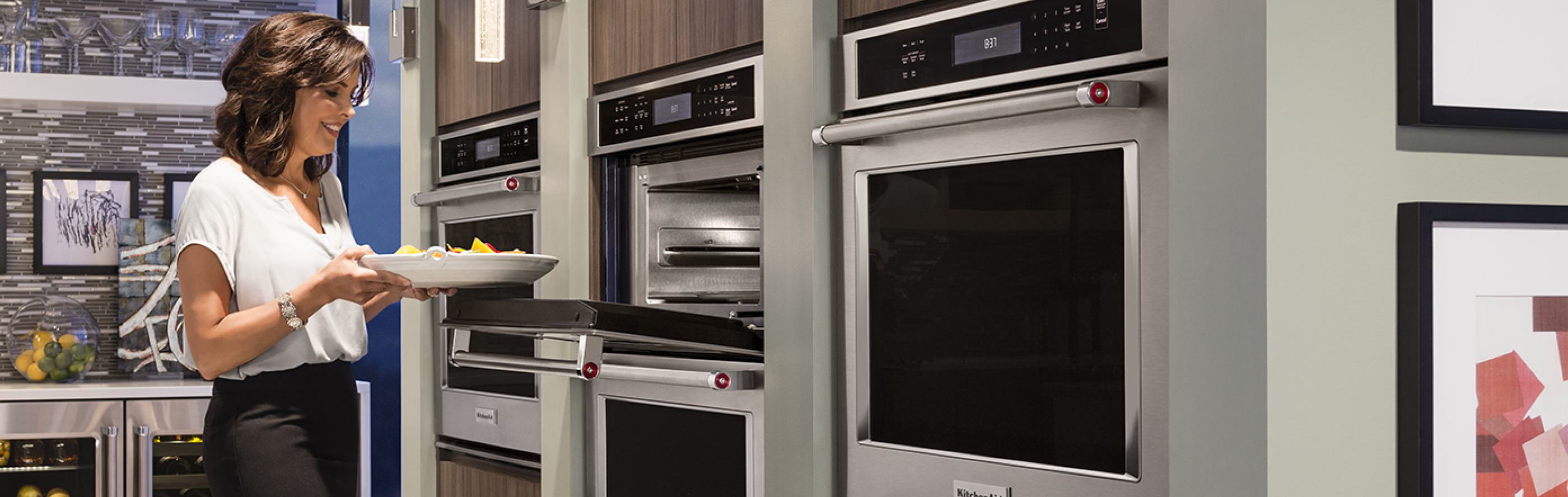 A woman placing a dish into a wall oven
