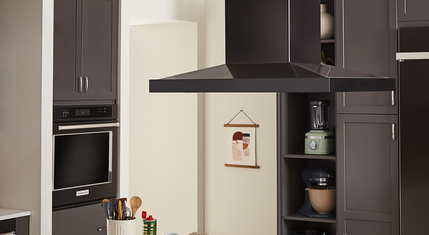 A vent hood and a single wall oven in a kitchen
