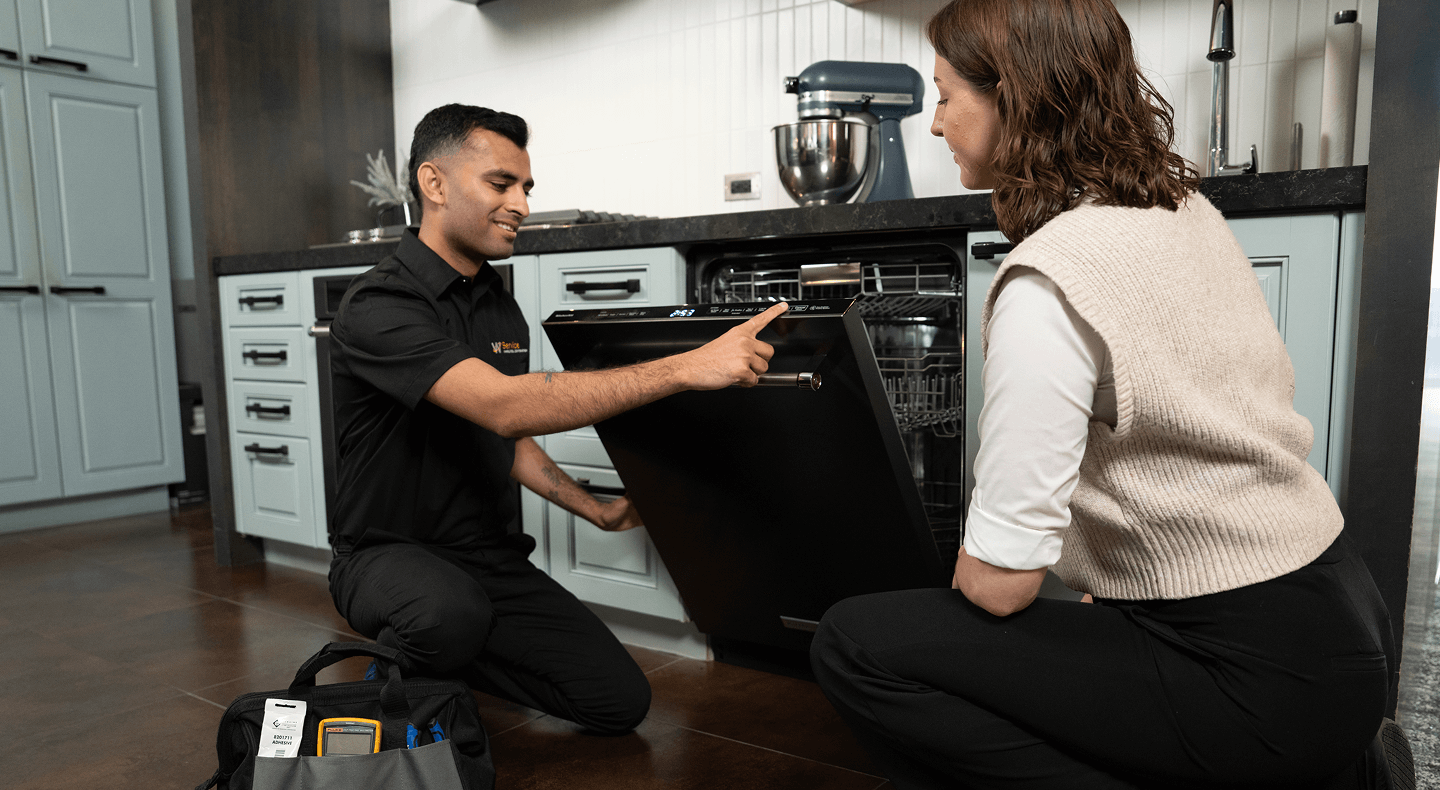 A technician helps a woman with her dishwasher