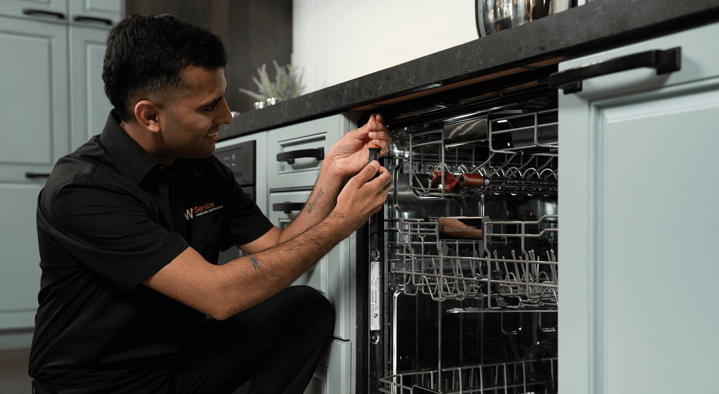 A technician works on a dishwasher