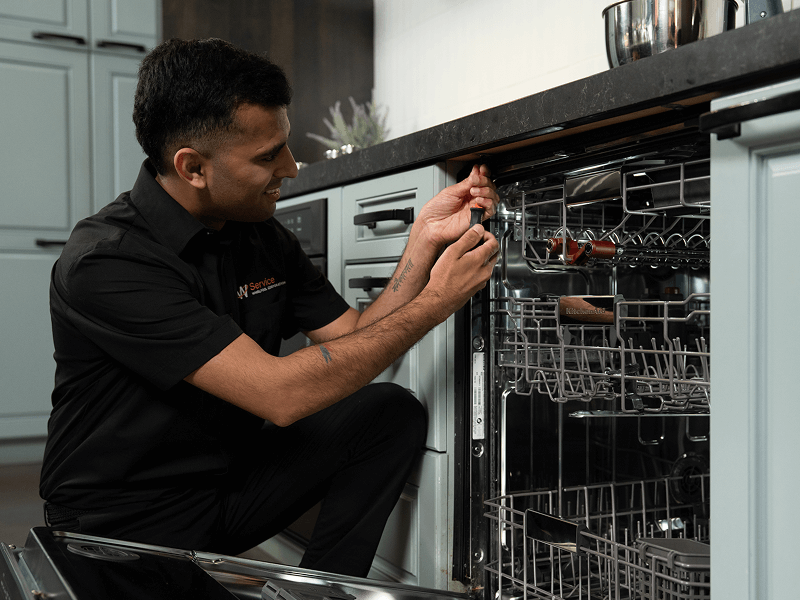 A technician works on a dishwasher