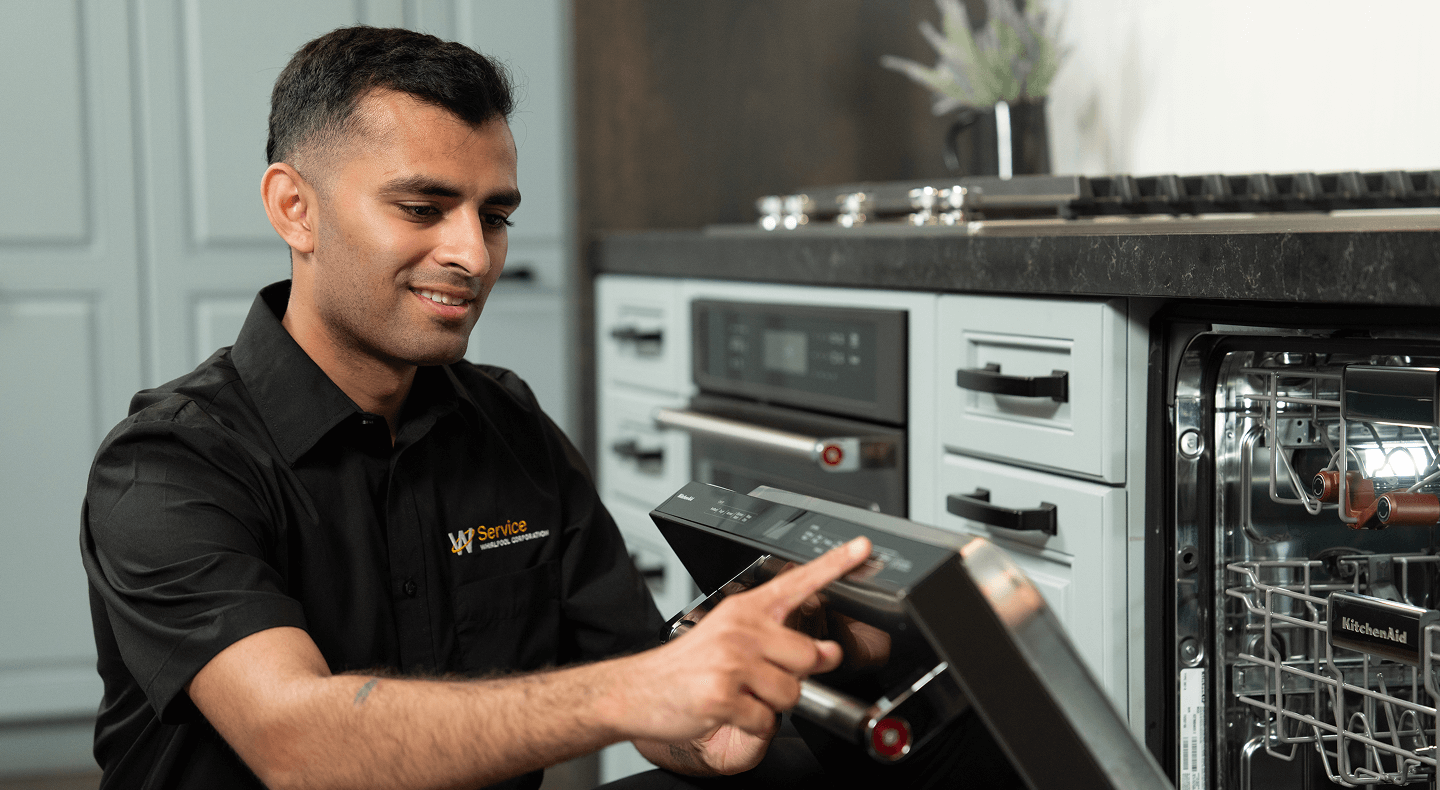 A technician works on a dishwasher