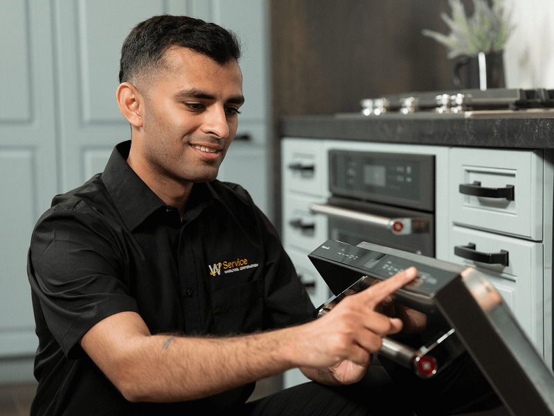 A technician works on a dishwasher