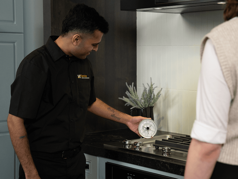 A technician helps someone with their cooktop