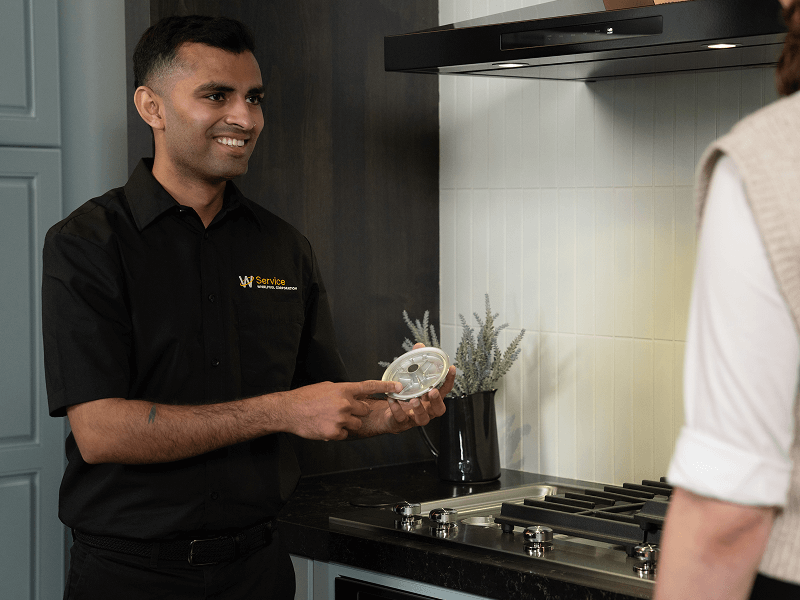 A technician helps someone with their cooktop