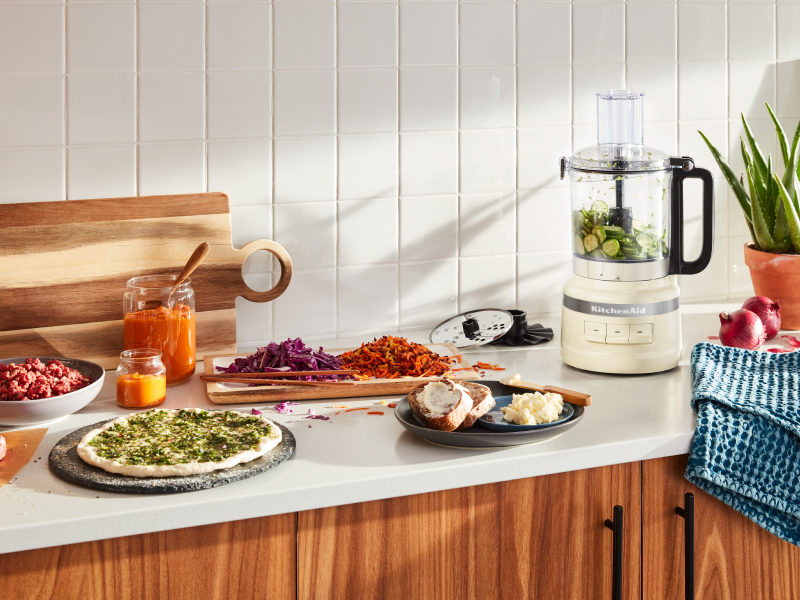 A KitchenAid® food processor with fresh vegetables in a modern kitchen.