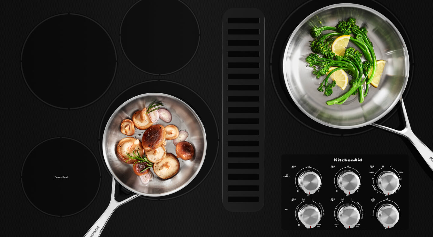 Two pans filled with vegetables on a cooktop