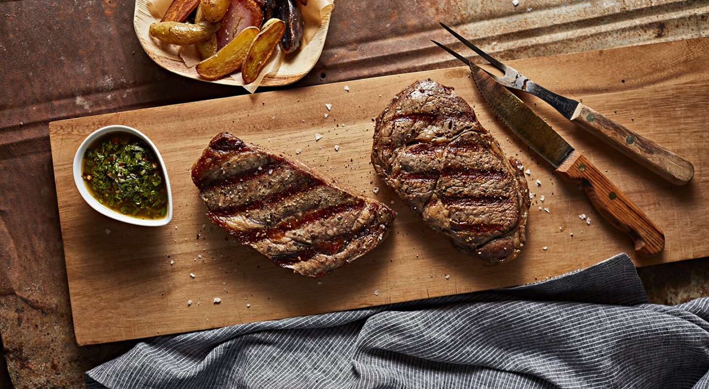 Two pieces of cooked steak on a cutting board