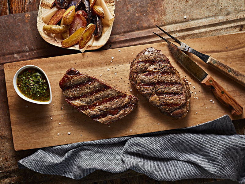 Two pieces of cooked steak on a cutting board