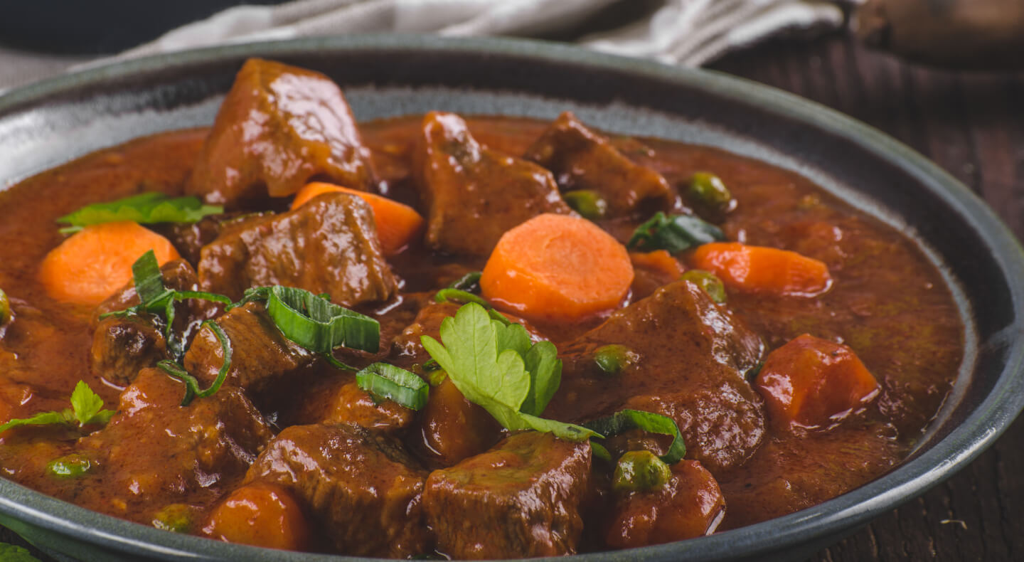 A bowl of stew with big chunks of meat and carrots