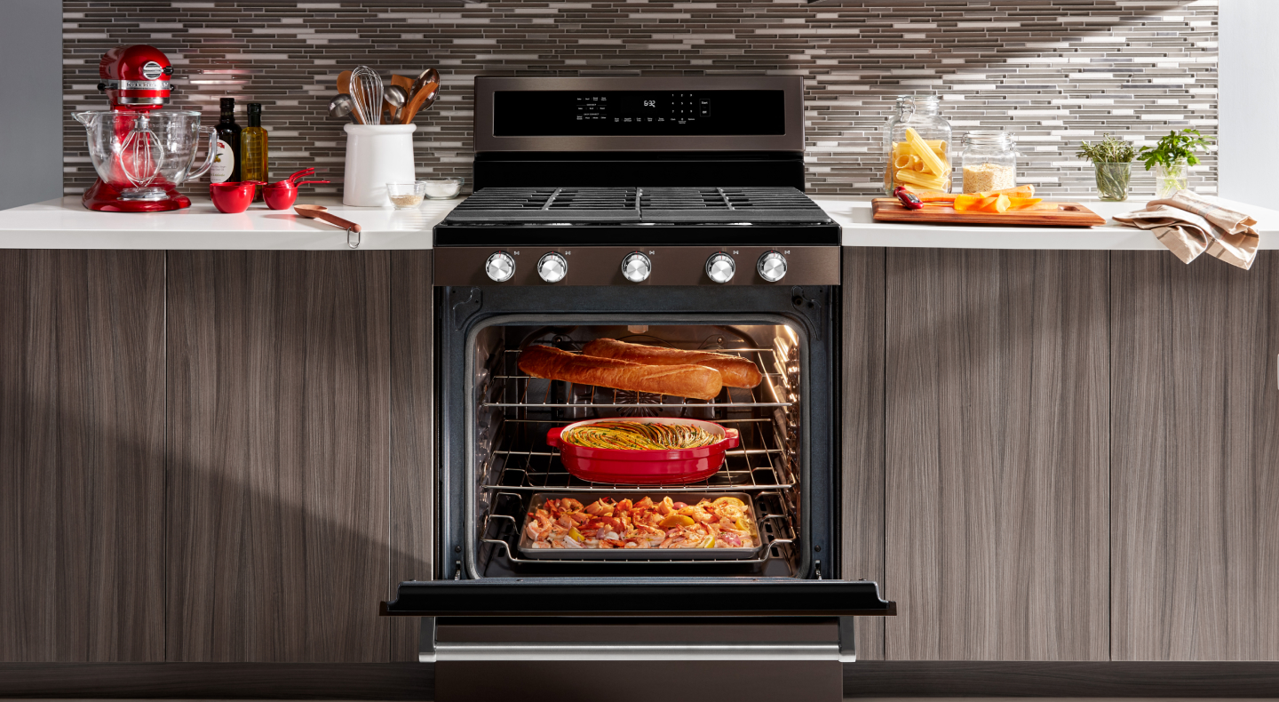 An open gas stove door filled with dishes cooking