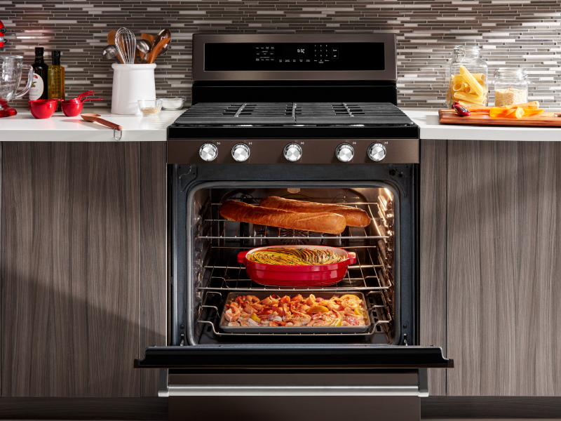 An open gas stove door filled with dishes cooking