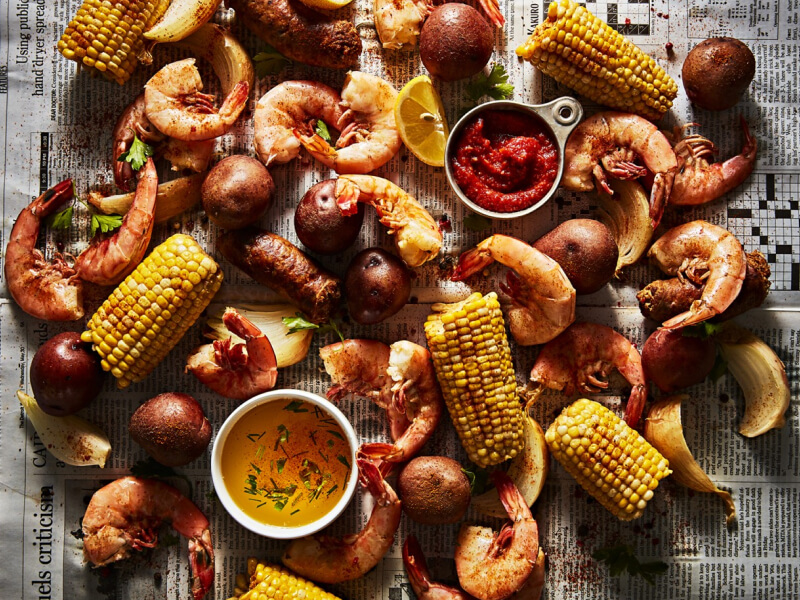 Shrimp, potatoes and corn spread out on a newspaper for a shrimp boil