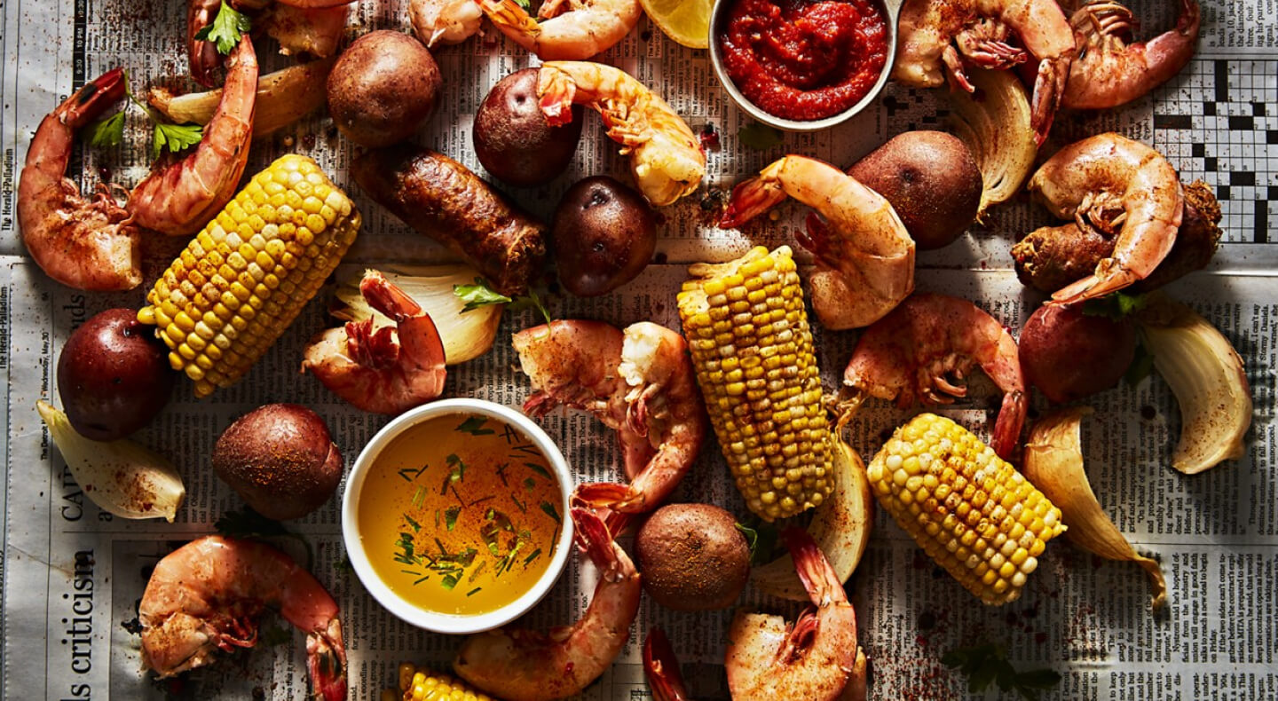 Shrimp, potatoes and corn spread out on a newspaper for a shrimp boil