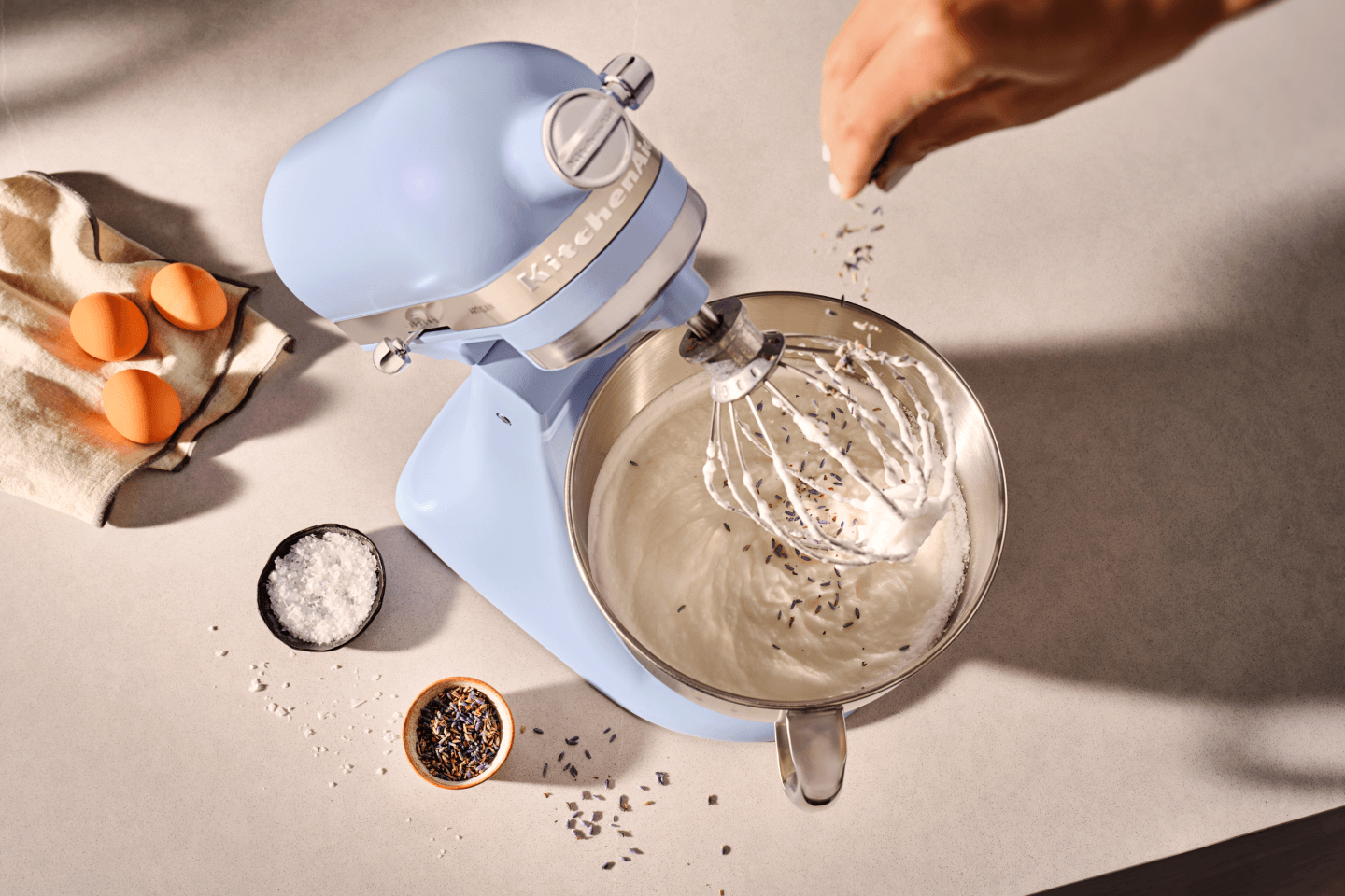 Person adding herbs to a KitchenAid® stand mixer in Blue Salt