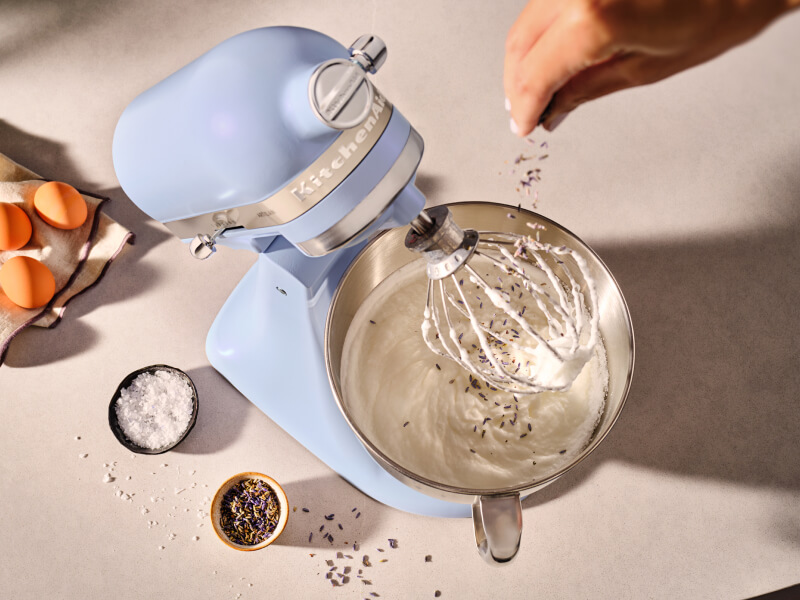 Person adding herbs to a KitchenAid® stand mixer in Blue Salt