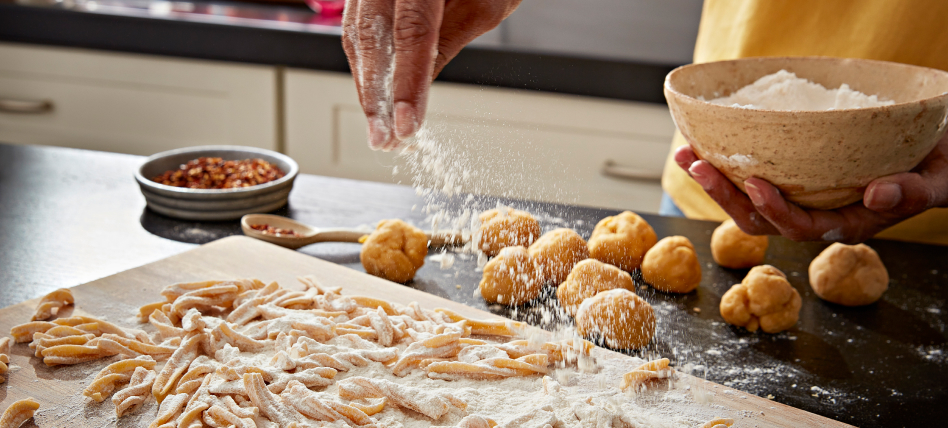 Hand sprinkling flour over fresh pasta