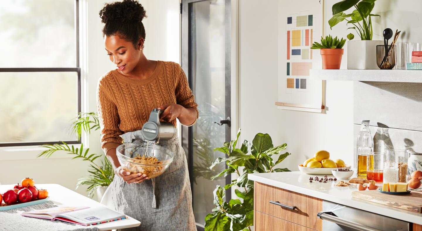 Person mixing ingredients with a KitchenAid® cordless hand mixer