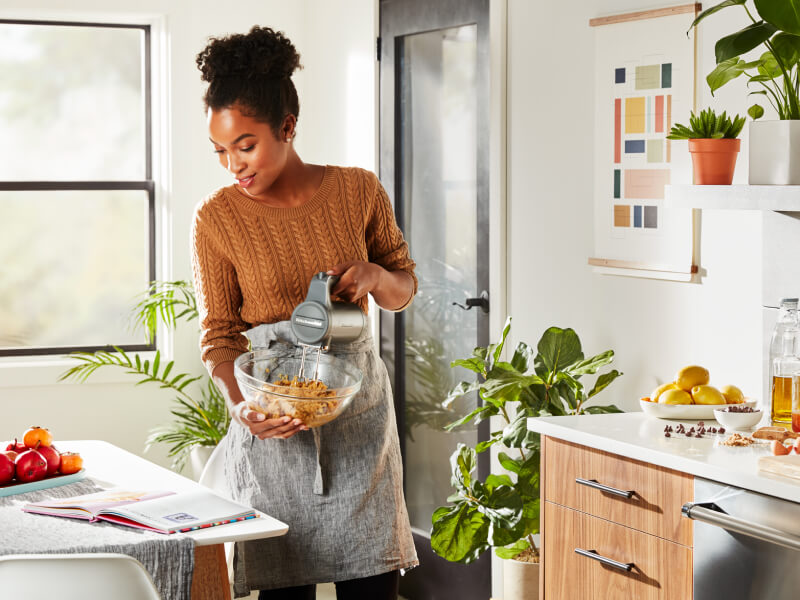 Person mixing ingredients with a KitchenAid® cordless hand mixer