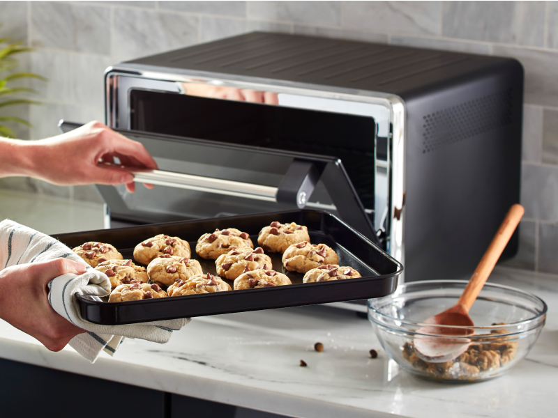 Tray of cookie dough going into a countertop oven