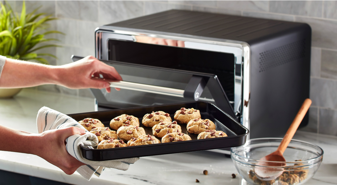 Tray of cookie dough going into a countertop oven