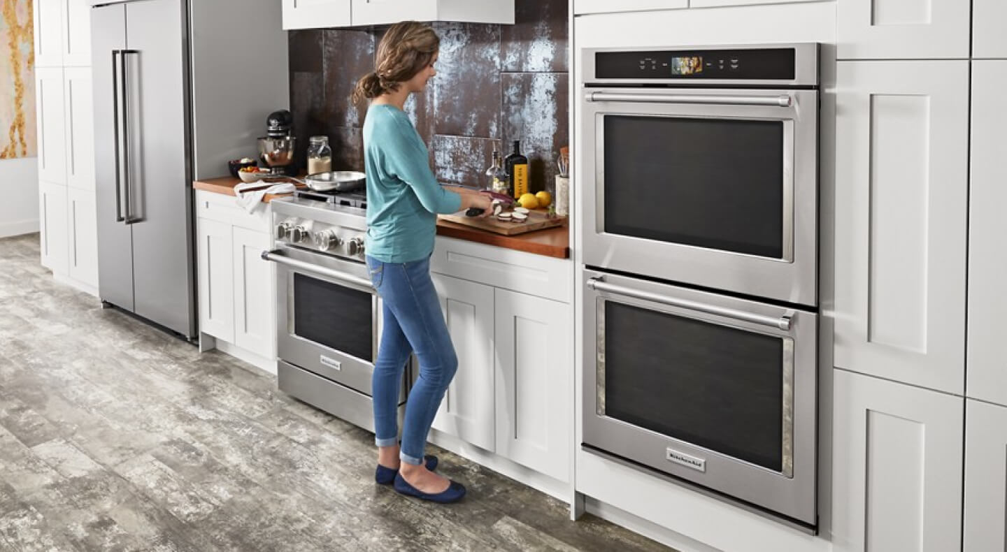 Person preparing food on the countertop next to a KitchenAid® double wall oven 