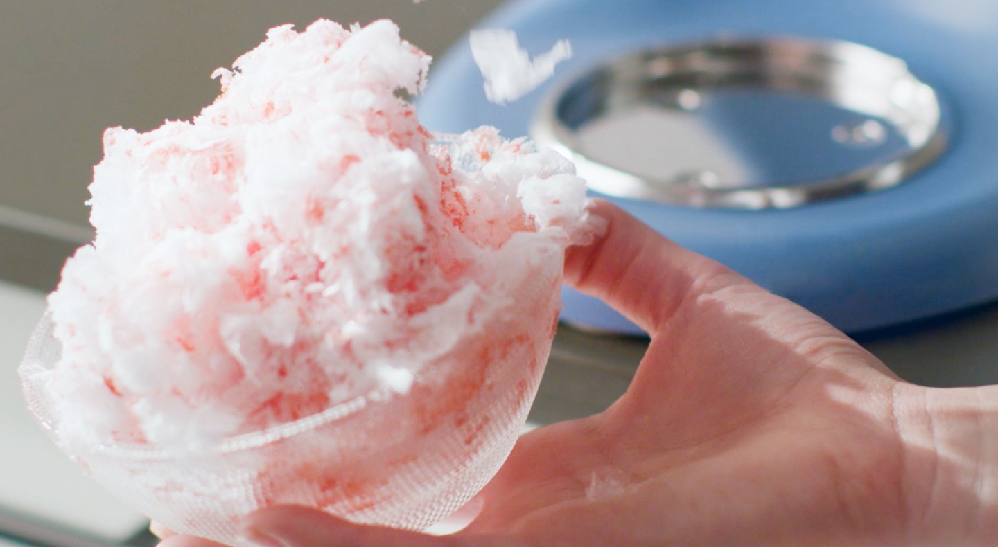 Fluffy shaved ice in front of a blue KitchenAid® stand mixer.