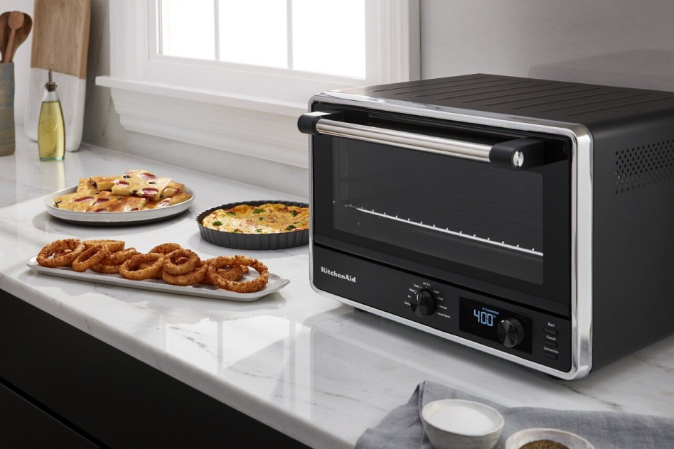 Air-fried onion rings on countertop next to KitchenAid® Countertop Oven with Air Fry. 