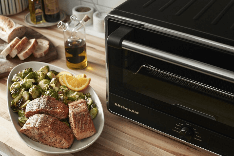 Air fryer vegetables and salmon next to a KitchenAid® Countertop Oven with Air Fry
