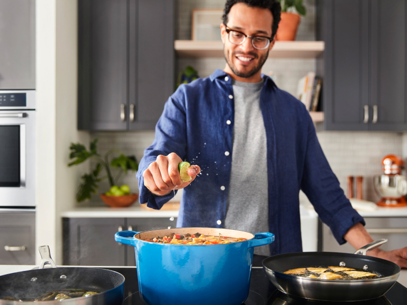 A man squeezing lime into a dish on a cooktop