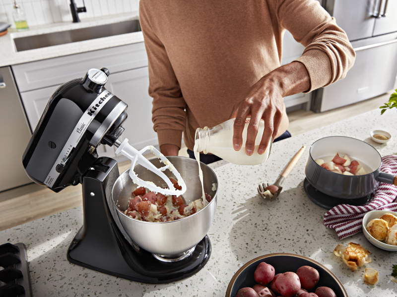 Person pouring milk into a KitchenAid® stand mixer bowl