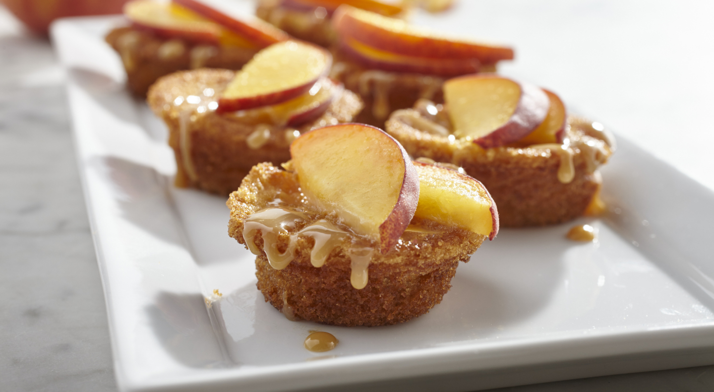 Muffins drizzled with caramel and topped with apple slices.