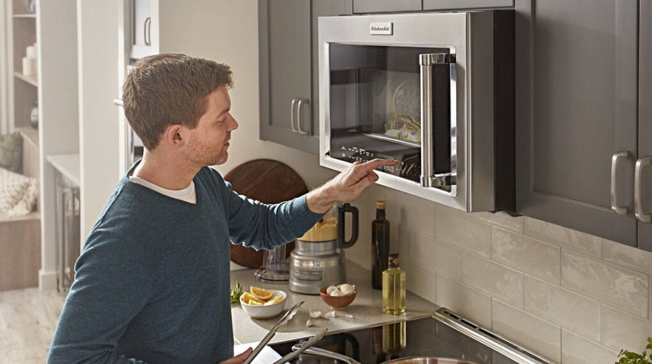 A person pressing the controls on a KitchenAid® microwave
