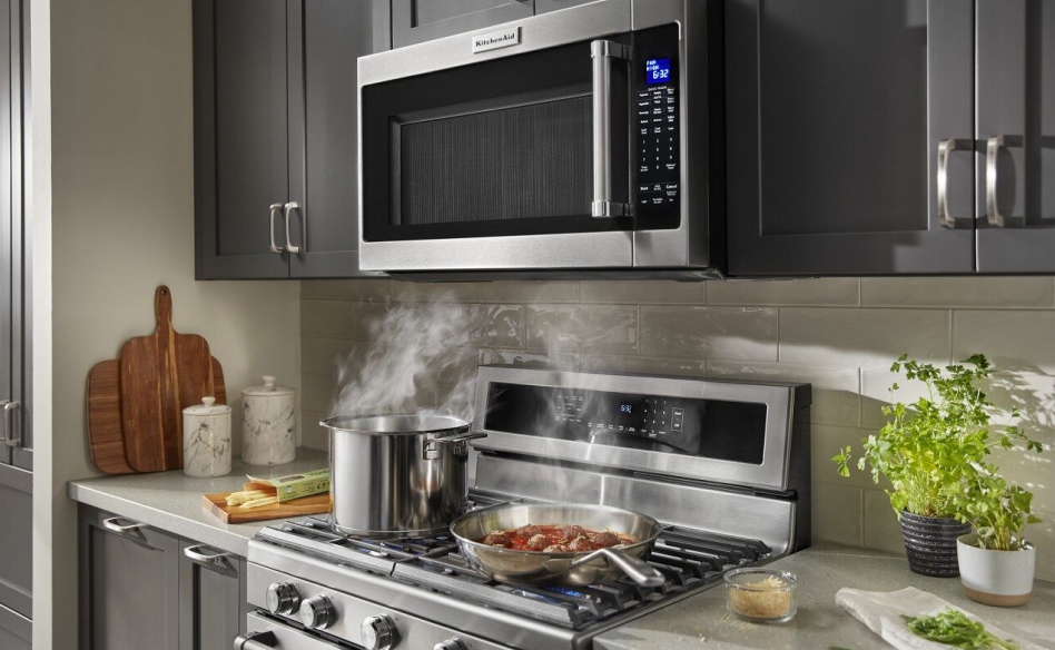 A KitchenAid® microwave installed over a range with food cooking on the different burners