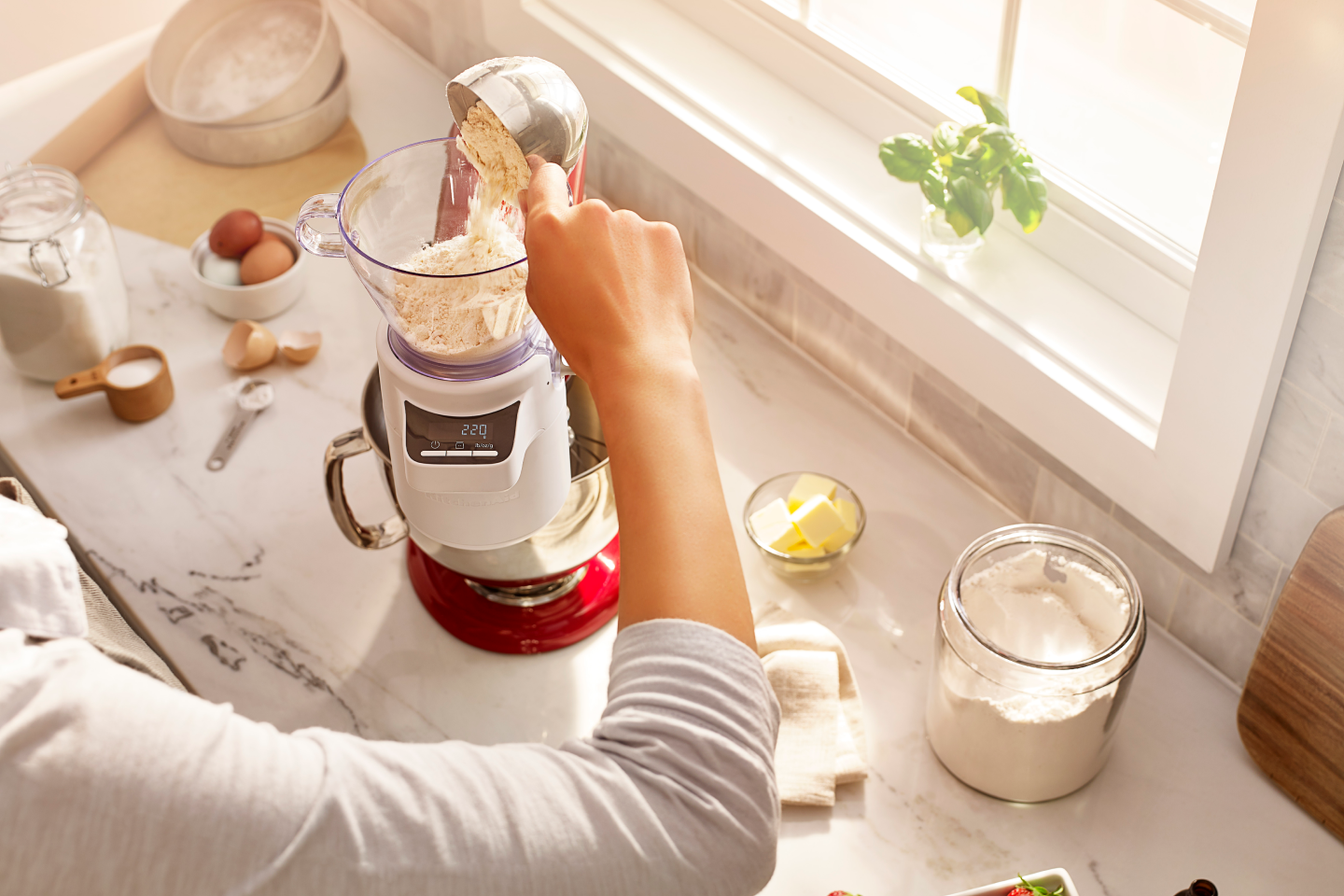 A person pouring flour into KitchenAid® Sifter & Scale Attachment.