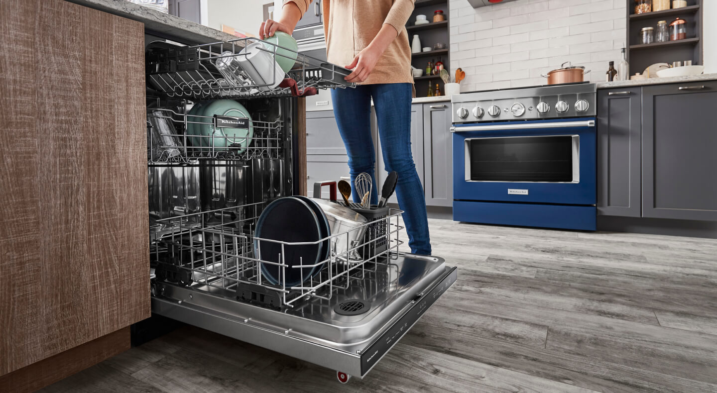 Woman loading dishes in a three rack dishwasher