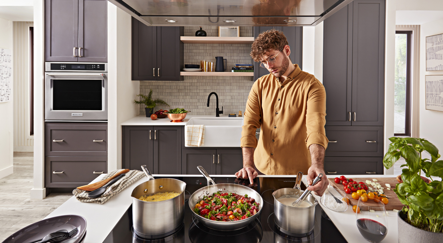 Person whisking food on the stovetop next to several cooking dishes