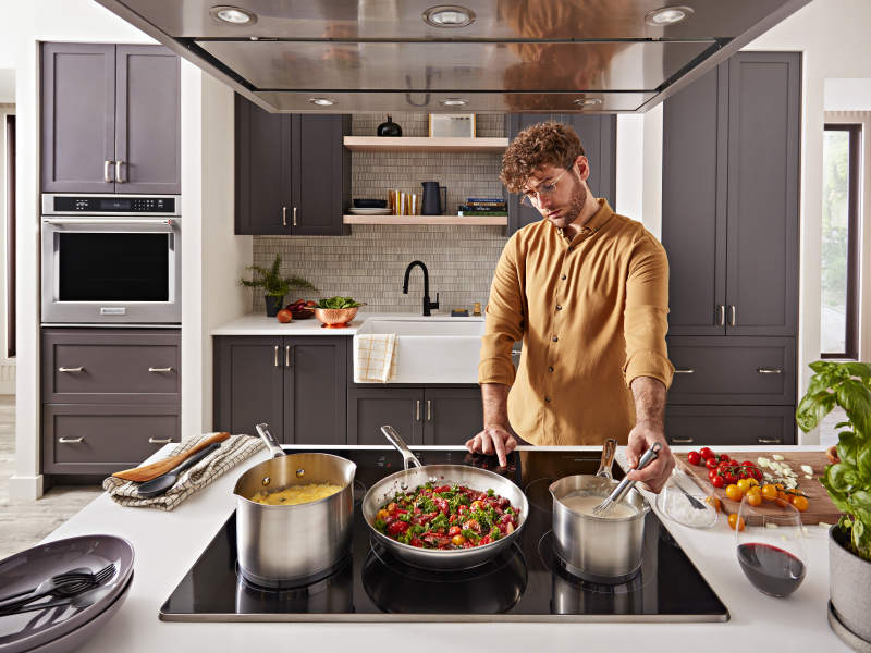 Person whisking food on the stovetop next to several cooking dishes