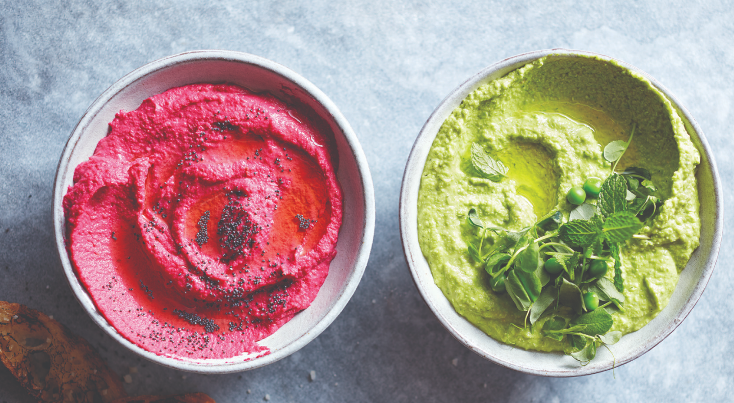Pink and green hummus topped with fresh herbs