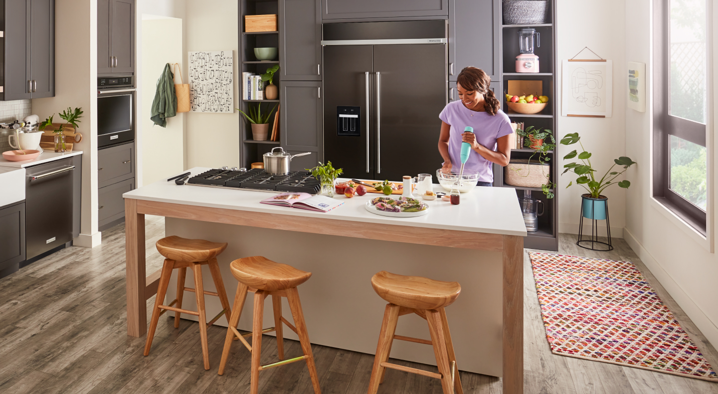 A woman using an immersion blender in a kitchen