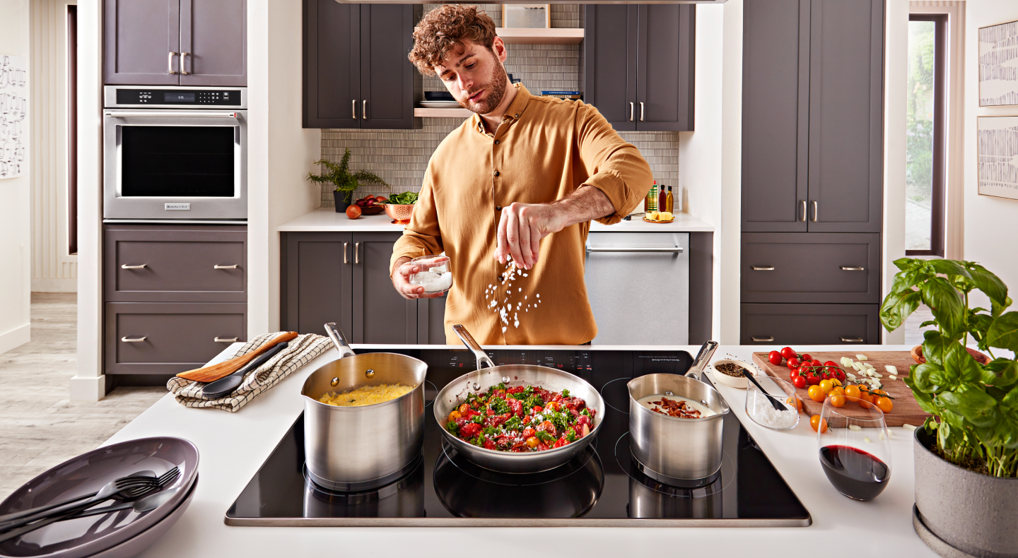 Person adding seasoning to a pan